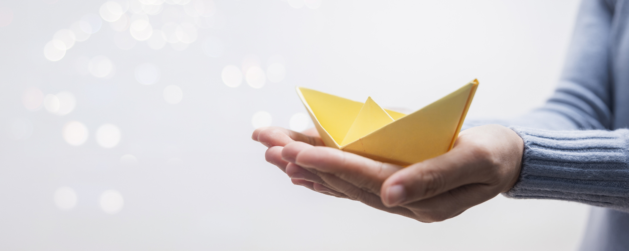 yellow paper boat on hand of woman leader